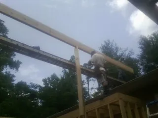 Carpenter setting a ridge beam over a new addition frame — Ice Dam Removal by Roofing Brothers in Petros