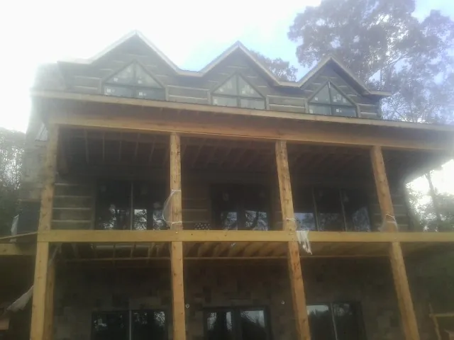 Dormers and porch framing on a large log home under construction — Roof Coating work by our crew in Petros