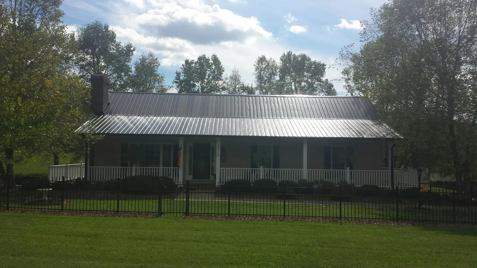Gray metal roof on a brick ranch with a full width front porch — Gutter Guard Installation work by our crew in Petros