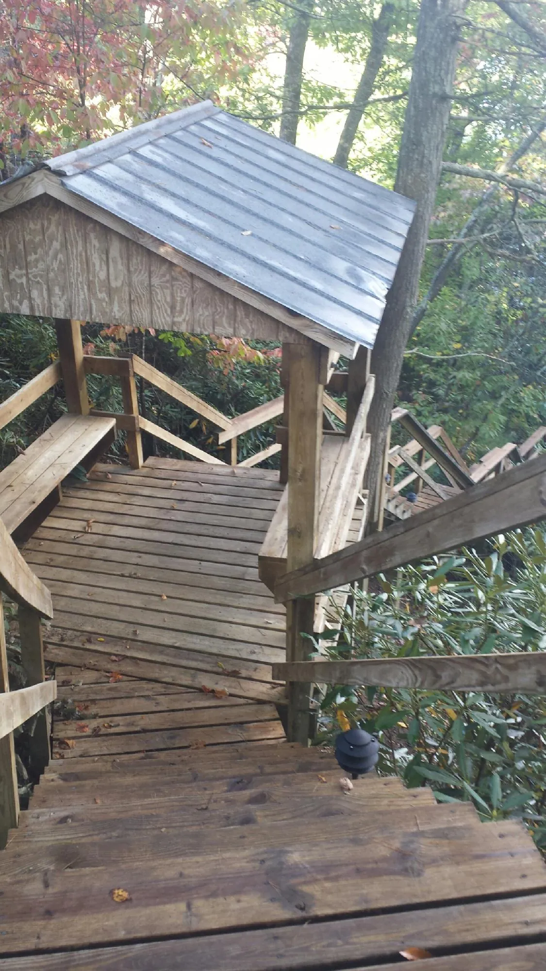 Metal roofed shelter over wooden steps on a wooded walkway — Skylight Repair & Installation work by our crew in Petros