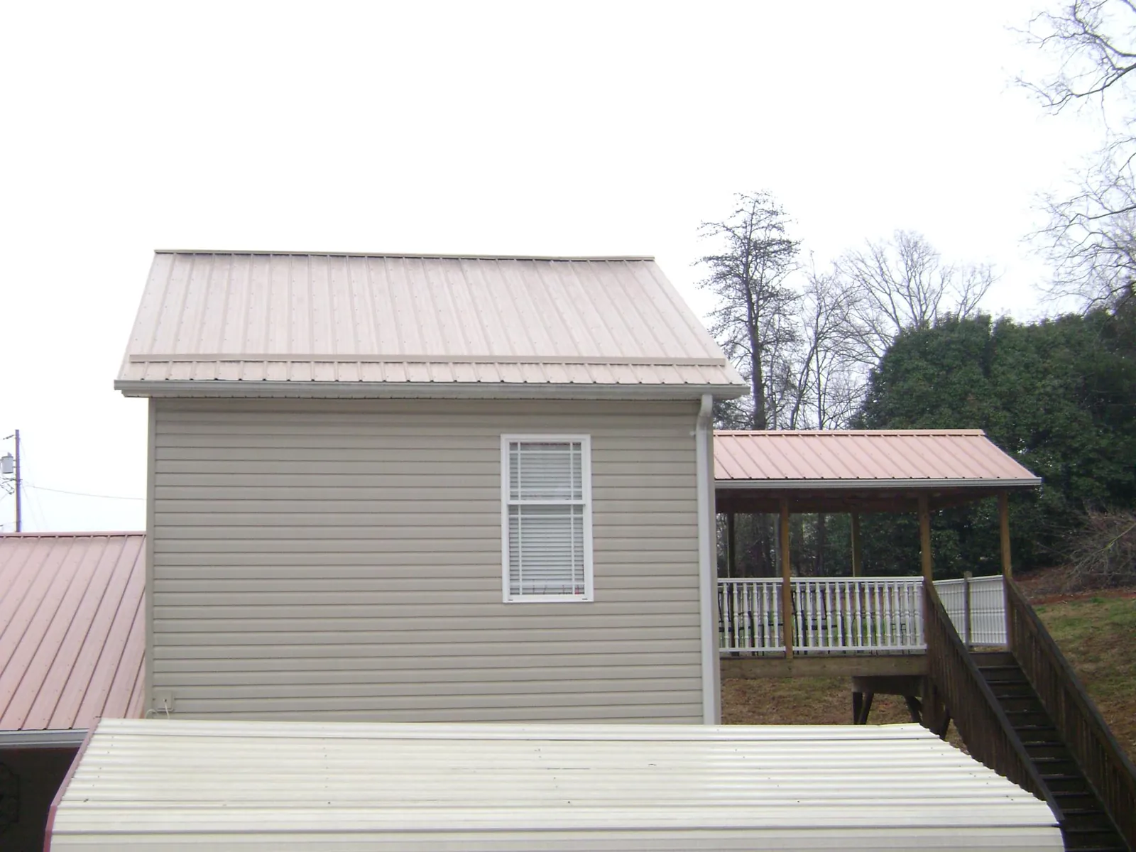 Tan metal roofs on a two story addition and attached porch in Petros