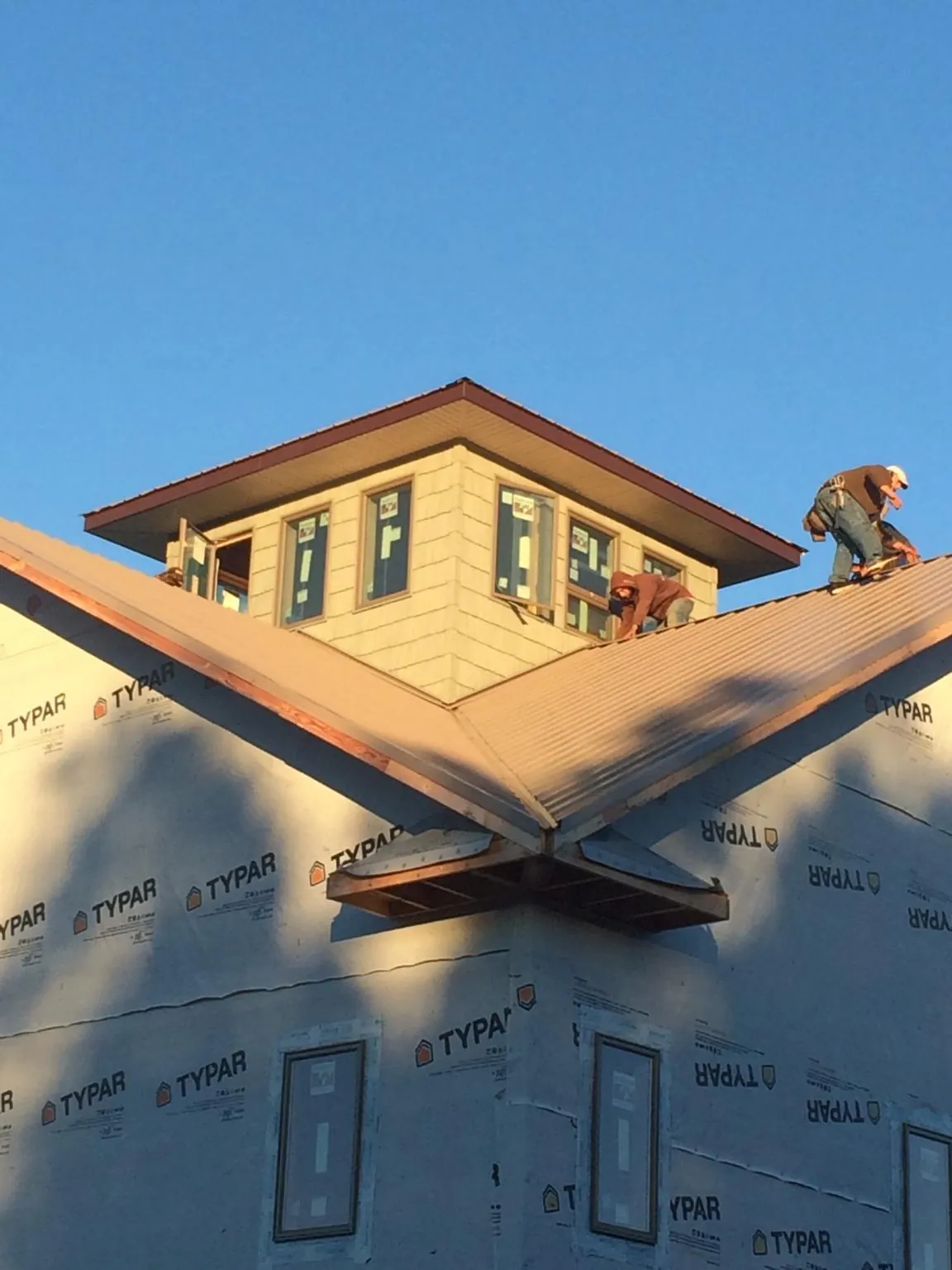 Roofers working around a rooftop cupola on a new metal roof at sunset — Roof Waterproofing in Petros by Roofing Brothers